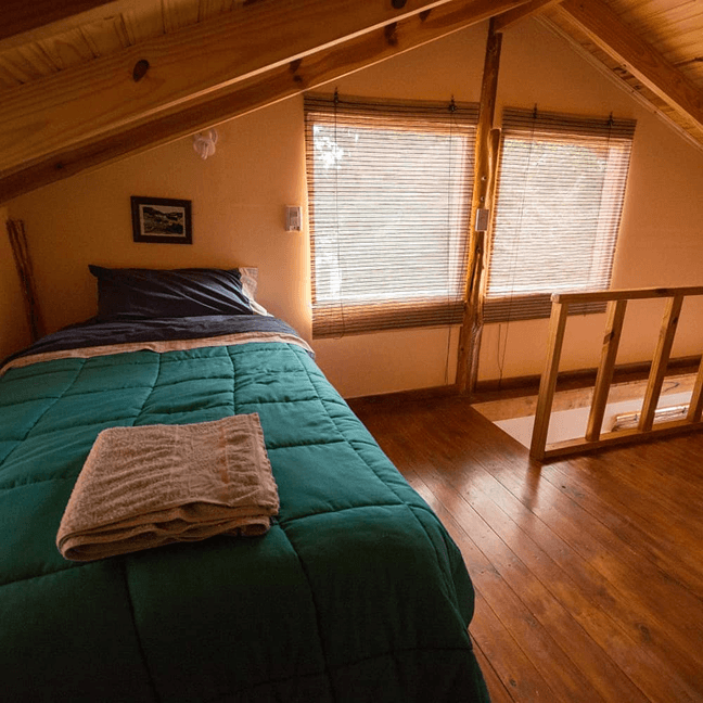 Dormitorio acogedor con cama y ventana en Cabañas Shautiau